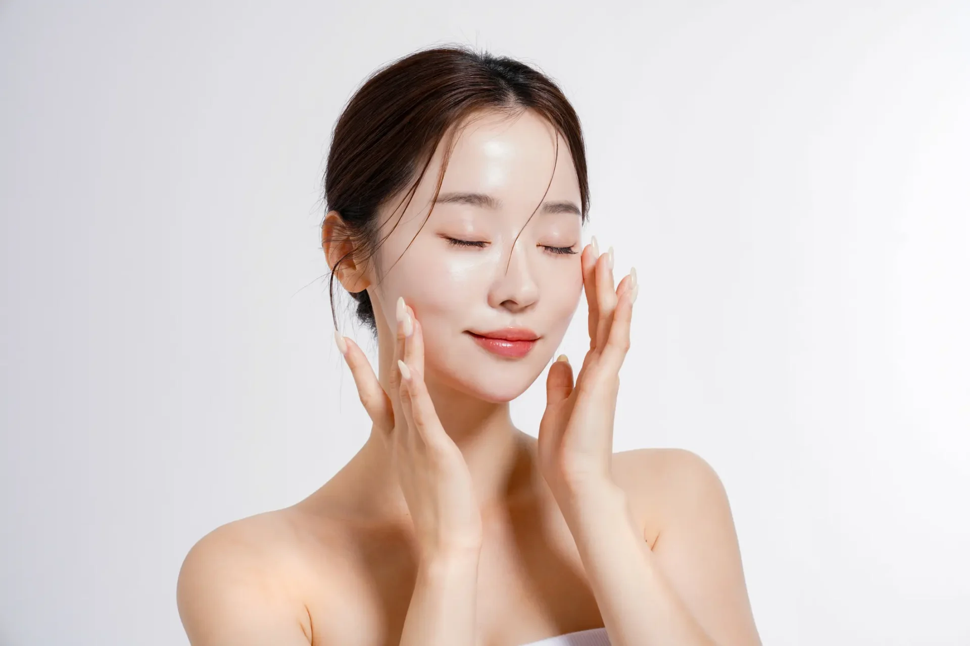 Woman applying skincare product on face.